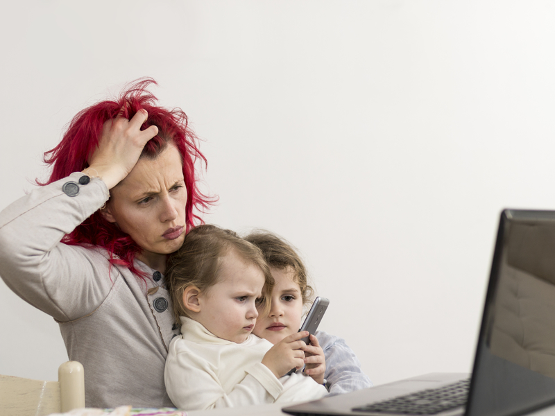 Une femme stressée travaillent sur son ordinateur avec deux enfants