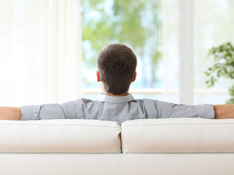 Un homme assis sur un divan regarde par la fenêtre