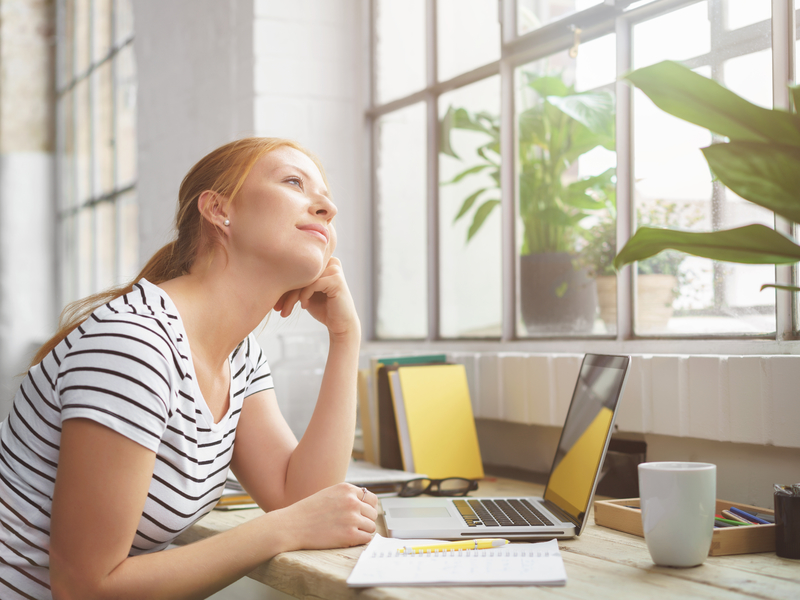 Jeune femme au travail regarde par la fenêtre