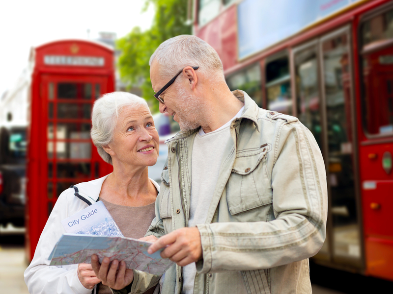 Un couple en vacances à Londres devant un bus rouge et une boite postale