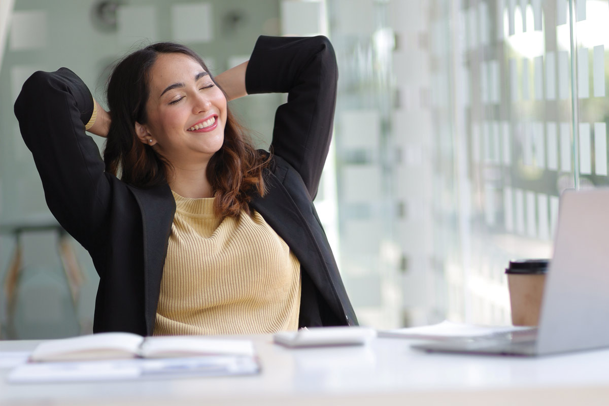 Femme souriante se détendant à son bureau